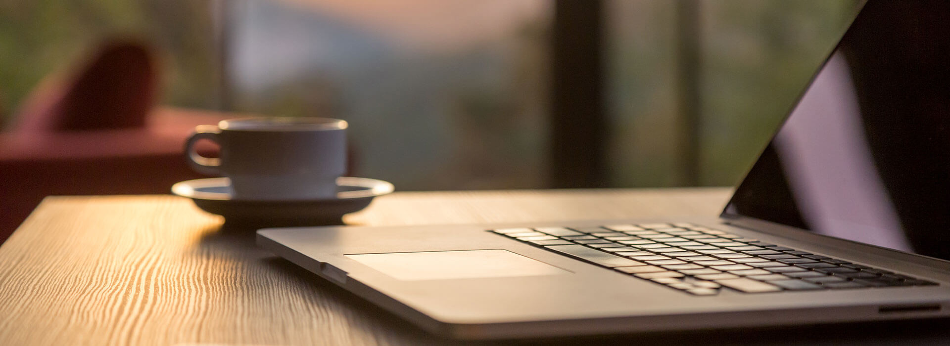 Ein Tisch auf dem eine Tasse und ein Laptop zu sehen sind.