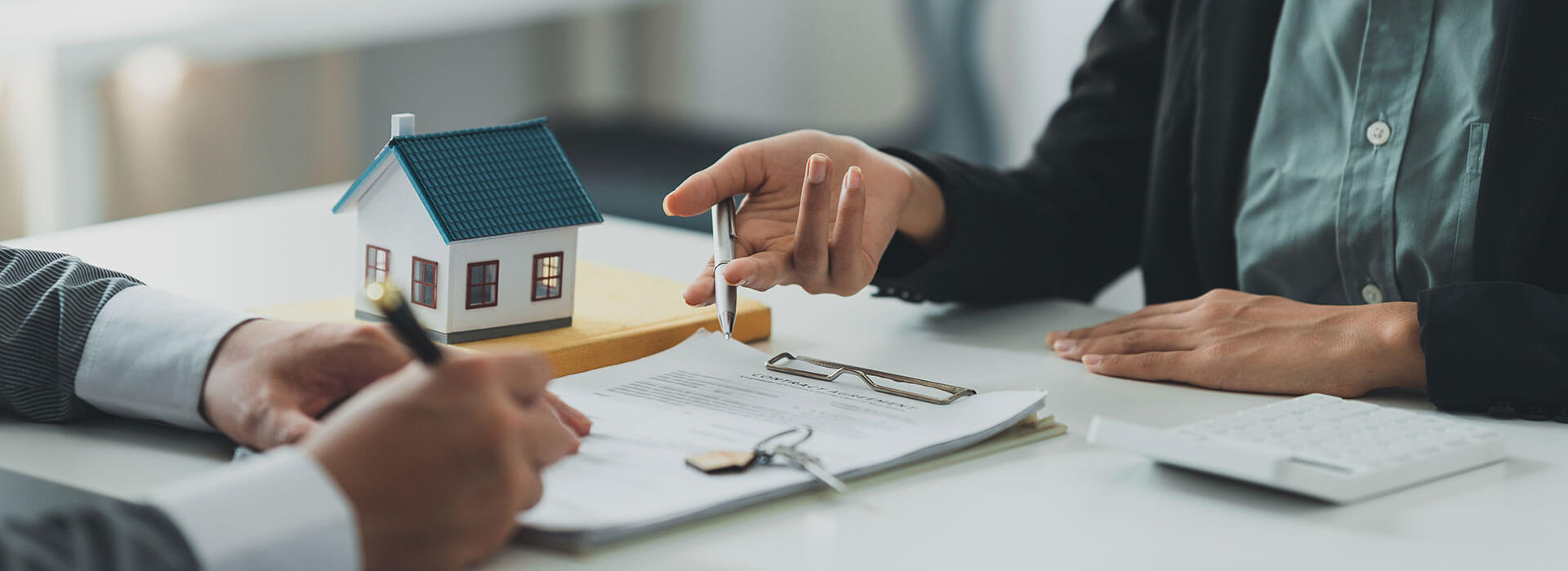 Zwei Menschen sitzen am Tisch und es wir über Immobilien gesprochen, da ein Haus daneben steht