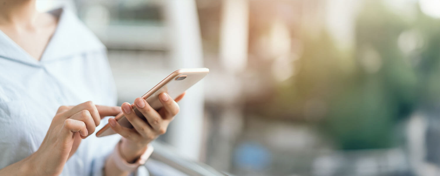 Eine Frau hält ein Handy in der Hand und tippt darauf